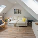 Wohnzimmer mit Sofa, Sessel, Couchtisch und Fenstern