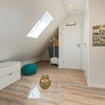 Schlafzimmer mit Dachschrägen, Fenster, Schrank und Fernseher.