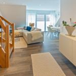 Wohn- und Essbereich mit Sofa, Tisch und Holztreppe