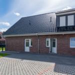 Rotes Backsteingebäude mit schwarzem Dach und weißer Tür