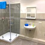 Badezimmer mit Dusche, Waschbecken und Spiegel.