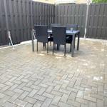 Terrasse mit Tisch und Stühlen, umgeben von dunklem Holzzaun.