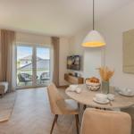 Essbereich mit runder Tisch und Stühlen, Wohnbereich mit Sofa und Balkonansicht.