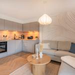 Küche mit Arbeitsplatte, Herd und Kühlschrank. Wohnbereich mit Sofa und runden Tisch.