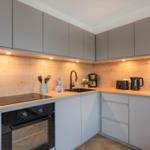 Moderne Küche mit grauen Schränken, Holzoberfläche und integriertem Backofen.