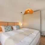 Schlafzimmer mit Bett, Nachttischen und Hängelampen.