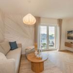 Wohnzimmer mit Sofa, TV und Balkonansicht.