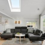 Wohnzimmer mit grauem Sofa, runder Tisch und großen Fenstern.