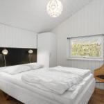 Schlafzimmer mit Bett, Stuhl und Fenster. Weiße Wände und Holzboden.