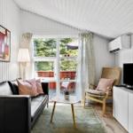 Wohnzimmer mit Sofa, Stuhl und TV. Blick auf Balkon mit Garten.