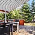 Terrasse mit Tisch und Stühlen, umgeben von Bäumen und Holzgeländern.