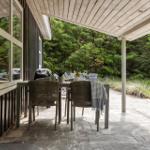 Terrasse mit Tisch und Stühlen, umgeben von Bäumen und Pflanzen.