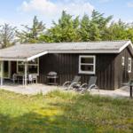Ein kleines Haus mit Terrasse, Liegestühlen und Grillplatz im Grünen.