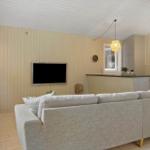 Wohnzimmer mit Sofa, Fernseher und Küchenbereich.