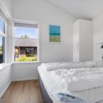 Schlafzimmer mit weißem Bett, Fenstern und Holzboden.