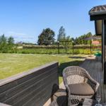Terrasse mit Sitzgelegenheiten und Blick auf Grünfläche und Schaukel.