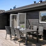 Terrasse mit Tisch und Stühlen vor einem Holzhaus mit offenen Türen.