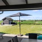 Terrasse mit Sonnenschirm und Blick auf grüne Wiesen und ein kleines Haus.