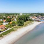 Strand nahe Hafen mit Häusern und Blick auf Felder