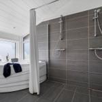 Bad mit Whirlpool, Dusche und großen Fenstern.