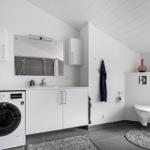 Badezimmer mit Waschmaschine, Spiegel und Toilette.