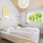 Schlafzimmer mit Doppelbett, Fenster und Holzdecke.