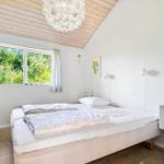 Schlafzimmer mit Doppelbett, Holzboden und Fenster mit Blick auf Grün.