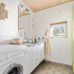 Badezimmer mit Waschmaschine, Spiegelschrank und grünem Duschvorhang.