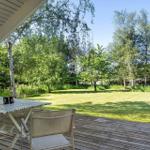 Terrasse mit Tisch und Stühlen, Blick auf grünen Garten und Bäume.