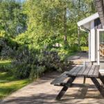 Holzterrasse mit Picknicktisch, Garten mit Schaukel und Sträuchern neben Haus