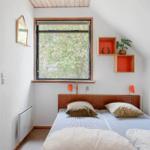 Schlafzimmer mit Dachschrägen, Fenster und Bett mit Kissen.