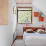 Schlafzimmer mit Dachschrägen, Fenster und Bett mit Kissen.