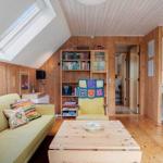 Wohnzimmer mit Sofa, Couchtisch und Bücherregal unter Dachschrägen.