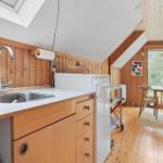 Küche mit Holzwand, Edelstahlspüle und Essbereich mit Tisch und Stühlen.