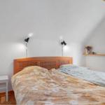 Schlafzimmer mit Holzbett, Fenster und Nachttisch.