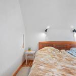 Schlafzimmer mit Holzbett, Nachttisch und Wandlampen.