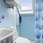 Badezimmer mit Dusche, Toilette und Waschbecken unter Dachfenster.