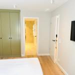 Schlafzimmer mit Bett, Kleiderschrank und TV. Tür führt in Bad.