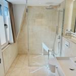 Badezimmer mit Dusche, Toilette und Waschbecken. Fenster mit Jalousie und Vorhang.