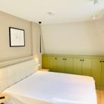 Schlafzimmer mit Bett, grüner Schrank und Wandbild.
