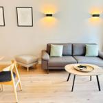 Wohnzimmer mit Sofa, Couchtisch und Stuhl. An der Wand hängen zwei Bilder und zwei Wandlampen.