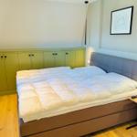 Schlafzimmer mit Bett, grünem Schrank und Wandbild.