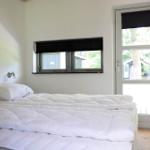 Bedroom with white bed, window, and door leading to outdoor area.