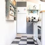 Kitchen with refrigerator, countertop, and black-and-white floor.