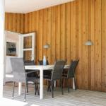 Deck with table and chairs, wooden wall and windows