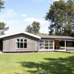 Wooden house with terrace, garden, and surrounding trees.