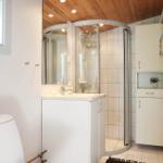 Bathroom with shower, sink and toilet. Wooden ceiling and white tiles.