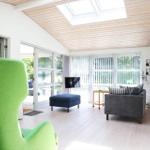 Living room with green armchair, sofa, and windows to the garden