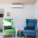 Two chairs, one green, one blue, are in a room with wooden ceiling and wall art.