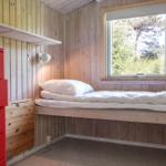 A bedroom with wooden walls, window, and red dresser.
